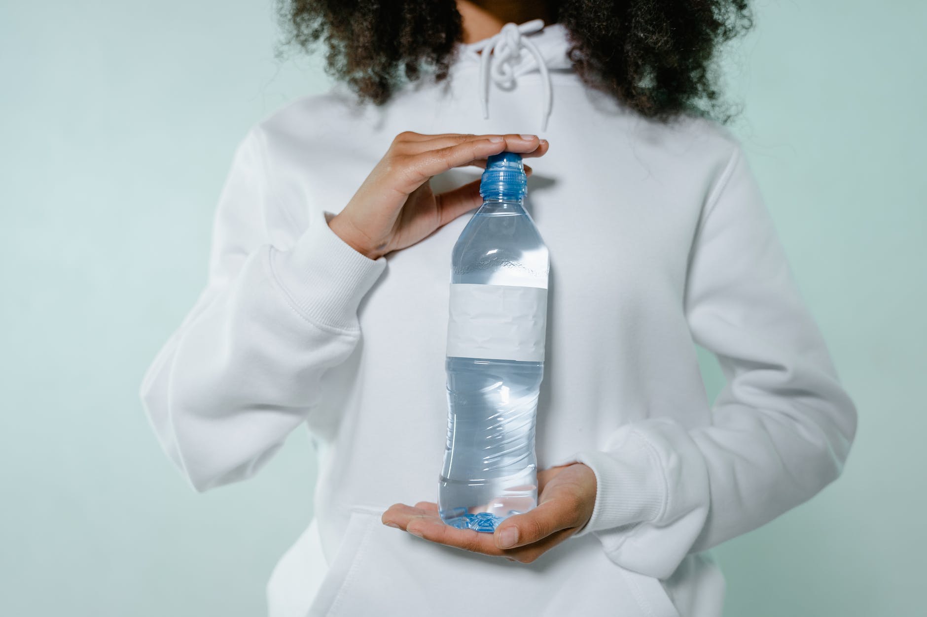 a woman in white sweater holding a water bottle