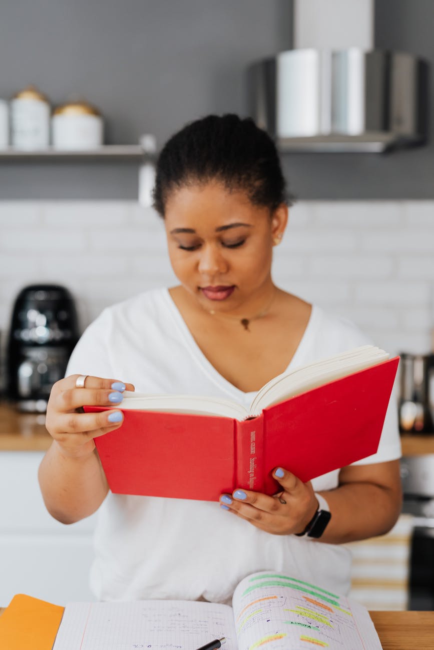 woman sitting behind a kitchen counter and reading a book
